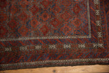Distressed Belouch rug border with primitive crab motifs, ruby red and sapphire blue hues.