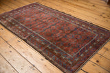 Vintage Distressed Belouch rug showing ruby red field, sapphire blue wave borders, and serrated guls.