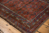 Distressed cherry red and sapphire blue Belouch rug corner with patterned border.