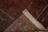 Folded vintage Belouch rug showing distressed red and blue pile, reverse weave, and intact selvage.