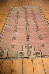 Distressed vintage Belouch rug with abrashed dusty rose field and floral gul medallions.