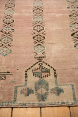 Distressed dusty rose Belouch rug showing geometric planter and gul medallion motifs.