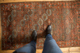 Distressed Belouch rug, geometric guls and lattice vinery in madder red and slate blue.