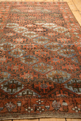 Vintage distressed Belouch rug with madder root red border and ivory vine motif.