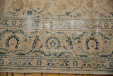 Distressed Kashan carpet end with intricate navy arabesques and floral palmettes on beige.