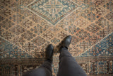 Distressed vintage Joshegan rug in beige and sky blue with garden motifs underfoot.