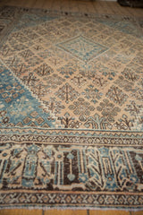 Distressed vintage Joshegan carpet, with worn beige field and blue-brown garden motifs.