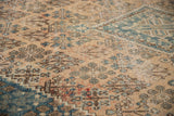 Distressed Joshegan carpet detail: beige field, sky blue garden motifs, visible foundation showing through.