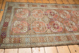 Distressed Belouch runner close-up, Bokhara guls, rams horn border, soft blush and blue tones.