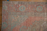 Detail of distressed Oushak runner showing low pile, faded blush, seafoam, and foundation through.