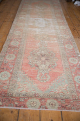 Fringed end of a distressed vintage Oushak runner, with muted rose and seafoam floral border.