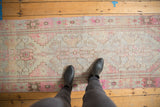 Faded pink and blue hues on a distressed vintage Oushak runner's worn pile.