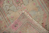 Texture of distressed Oushak rug pile in fuchsia, soft beige, and blue, with visible reverse foundation.