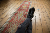 Distressed Oushak runner's elongated medallion and hook motifs in cherry red, saffron yellow.