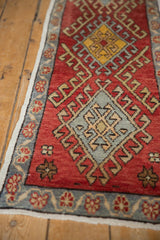 Distressed vintage Oushak runner shows abrashed red field, geometric diamond motif, slate blue floral border.