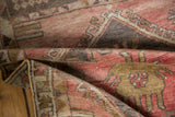 Vintage distressed Oushak runner's textured pile, muted rose, bronze, and charcoal patterns.