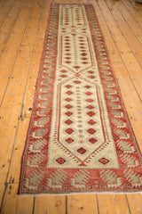 Finned motifs in dusty red and beige on the distressed Oushak runner border.