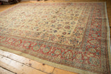 Corner view of a distressed Persian Tabriz carpet with a detailed cherry red floral border.