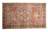Vintage distressed Oushak carpet with a large scalloped medallion in violet purple, cherry red, and sand.