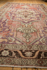 Low-angle perspective showing the worn knot heads and medallion finial of a distressed Oushak carpet.