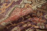 Distressed hand-knotted pile of a vintage Oushak rug in faded violet, red, and sand tones.