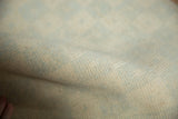 Distressed Oushak rug pile texture with faded ivory and mint green checkered pattern.