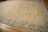 Distressed vintage Oushak carpet, faded ivory field with pale blue floral vinery and border.