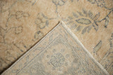 Distressed Oushak rug corner, revealing even wear to pile, faint foundation, and intact selvage.