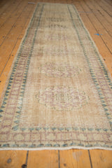 Side view of distressed vintage Oushak runner with worn pile, visible foundation, intact selvage.