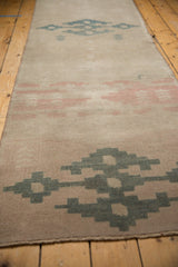 Distressed texture and geometric patterns on a vintage Oushak runner with dusty rose and teal tones.