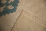 Distressed geometric dusty teal pile folds over the hand-knotted foundation and secured edge.