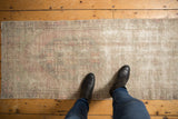 Distressed vintage Oushak runner's texture, showing faded pale mauve, seafoam, and ivory tones.