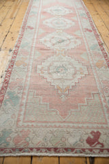 Distressed vintage Oushak runner with faded dusty rose, seafoam, and neutral stepped geometric design.