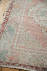 Textural distressed Oushak runner with faded rose and seafoam green motifs.