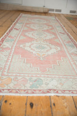Distressed Oushak runner detail: muted rose, seafoam green geometric motifs with visible foundation.