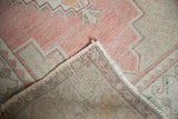 Faded rose and green distressed Oushak pile, revealing natural foundation and selvage.