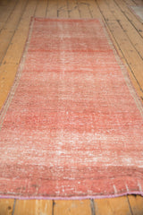 Texture and striations visible on the distressed Oushak runner's faded raspberry field.