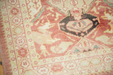 Distressed Oushak runner corner, revealing blush and red geometric border and central finned motif.