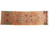 Vintage distressed Oushak runner with geometric stepped medallions in faded raspberry, turquoise, and tangerine.