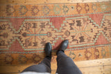 A personal view looking down at the distressed texture and geometric patterns of a vintage Oushak runner.