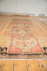 Angled perspective along a vintage Oushak runner with faded raspberry and turquoise geometric medallions.