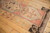 Low-pile texture and stepped medallions in raspberry and turquoise on a vintage Oushak runner.