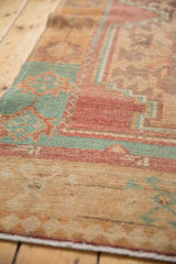 Mostly even wear on the low pile of a Turkish Oushak rug in raspberry, turquoise, and sand tones.