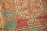 Textured, worn pile on a vintage Oushak rug with raspberry and faded turquoise geometric patterns.
