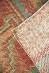 The hand-knotted foundation and distressed low pile of a vintage Oushak runner.