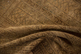 Distressed pile texture of a Turkmen rug, showing muted beige-gold geometric and crab motifs.
