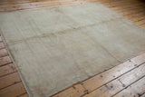 Distressed vintage Oushak rug texture revealing muted ivory, pale blush, and gold motifs.