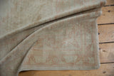 Distressed ivory vintage Oushak rug with a pale blush geometric border and secured selvage.
