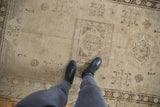Distressed vintage Khotan rug showing visible wear and muted squared floral gul patterns.