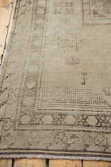 Distressed Khotan rug showing worn beige pile, visible foundation, and geometric border.